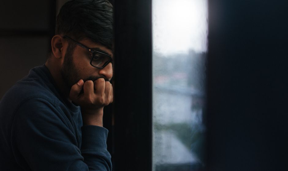 Contemplative man gazing out a rainy window, lost in thought.